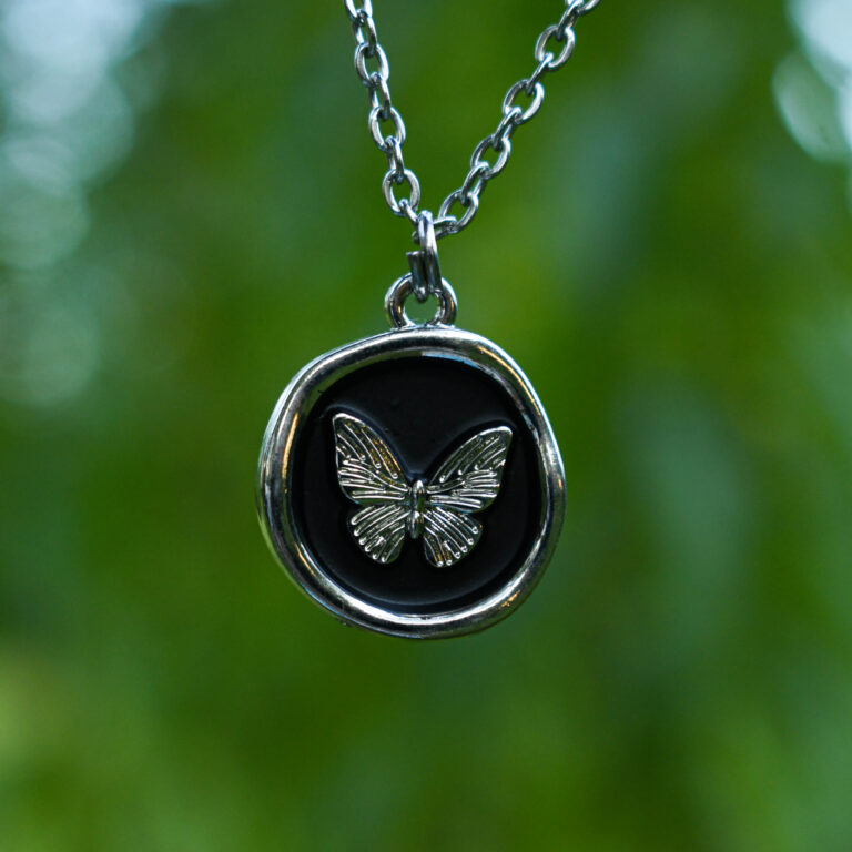 Liblikas mustal taustal ümmarguses ripatsis