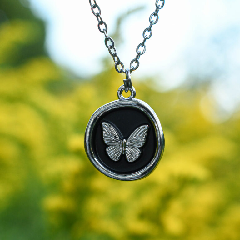 Liblikas mustal taustal ümmarguses ripatsis