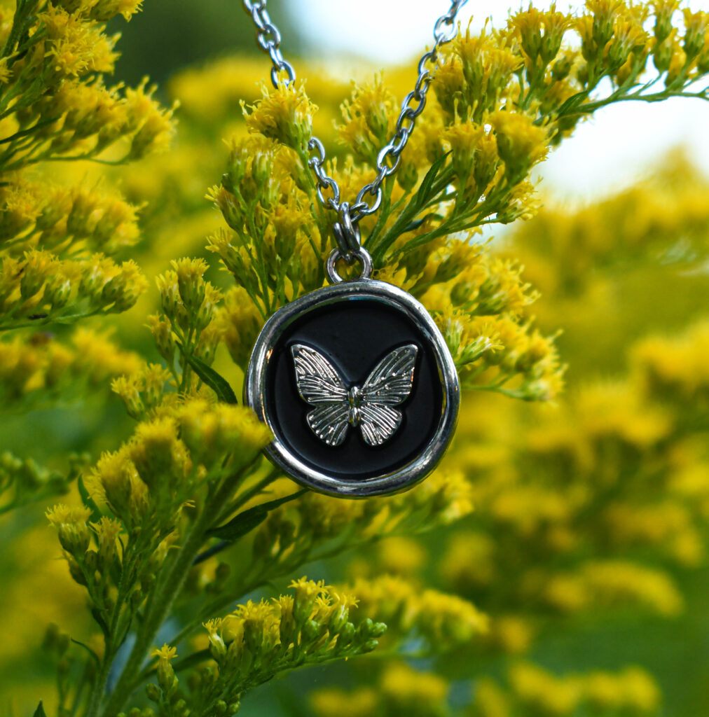 Liblikas mustal taustal ümmarguses ripatsis