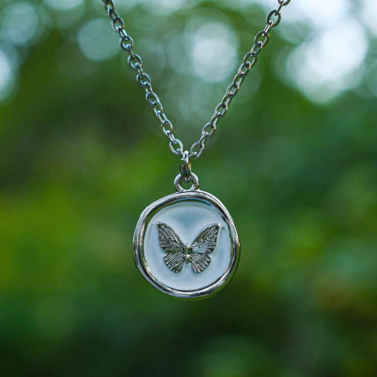 Liblikas valgel taustal ümmarguses ripatsis