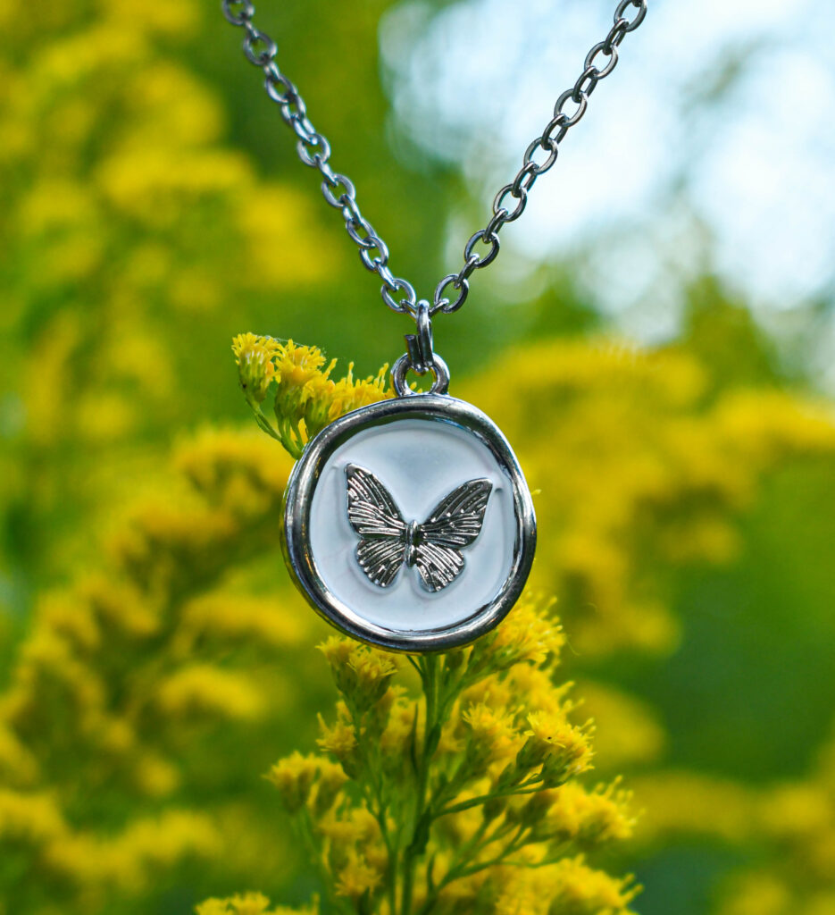 Liblikas valgel taustal ümmarguses ripatsis