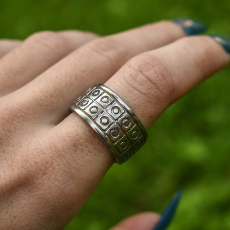 Lusikasõrmuse lähivõte sõrmes, näha on ringidega ruudumuster ja siledad servaribad.